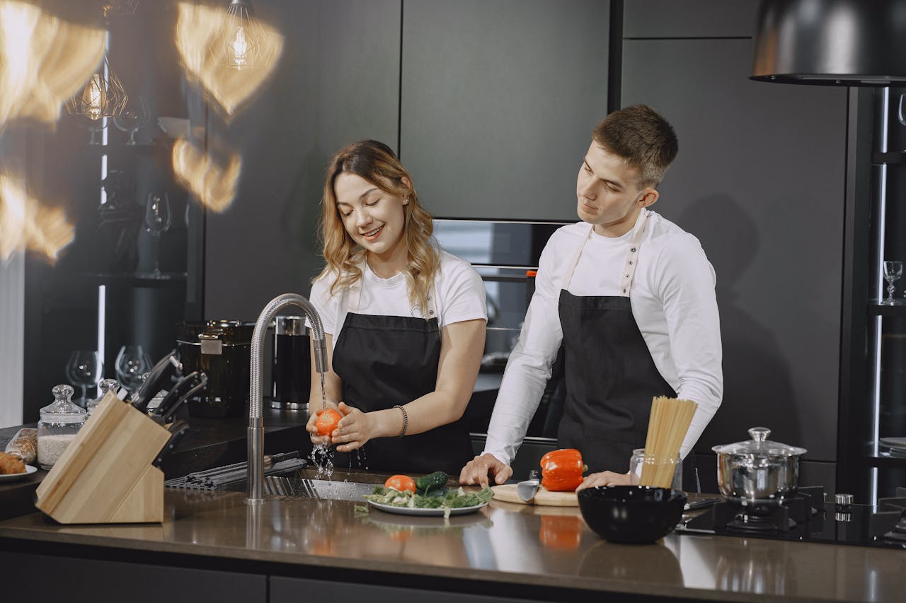 Smiling couple preparing food together in a sleek and modern kitchen setting, fostering togetherness and joy.
